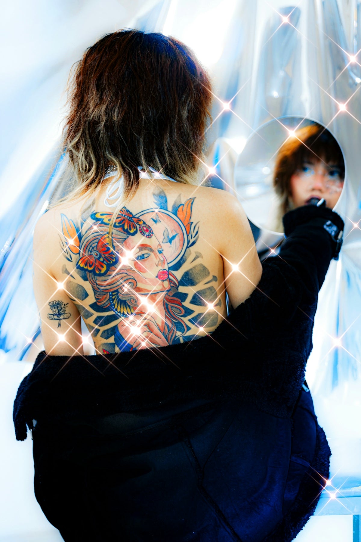 A person with a back tattoo looks in a mirror.
