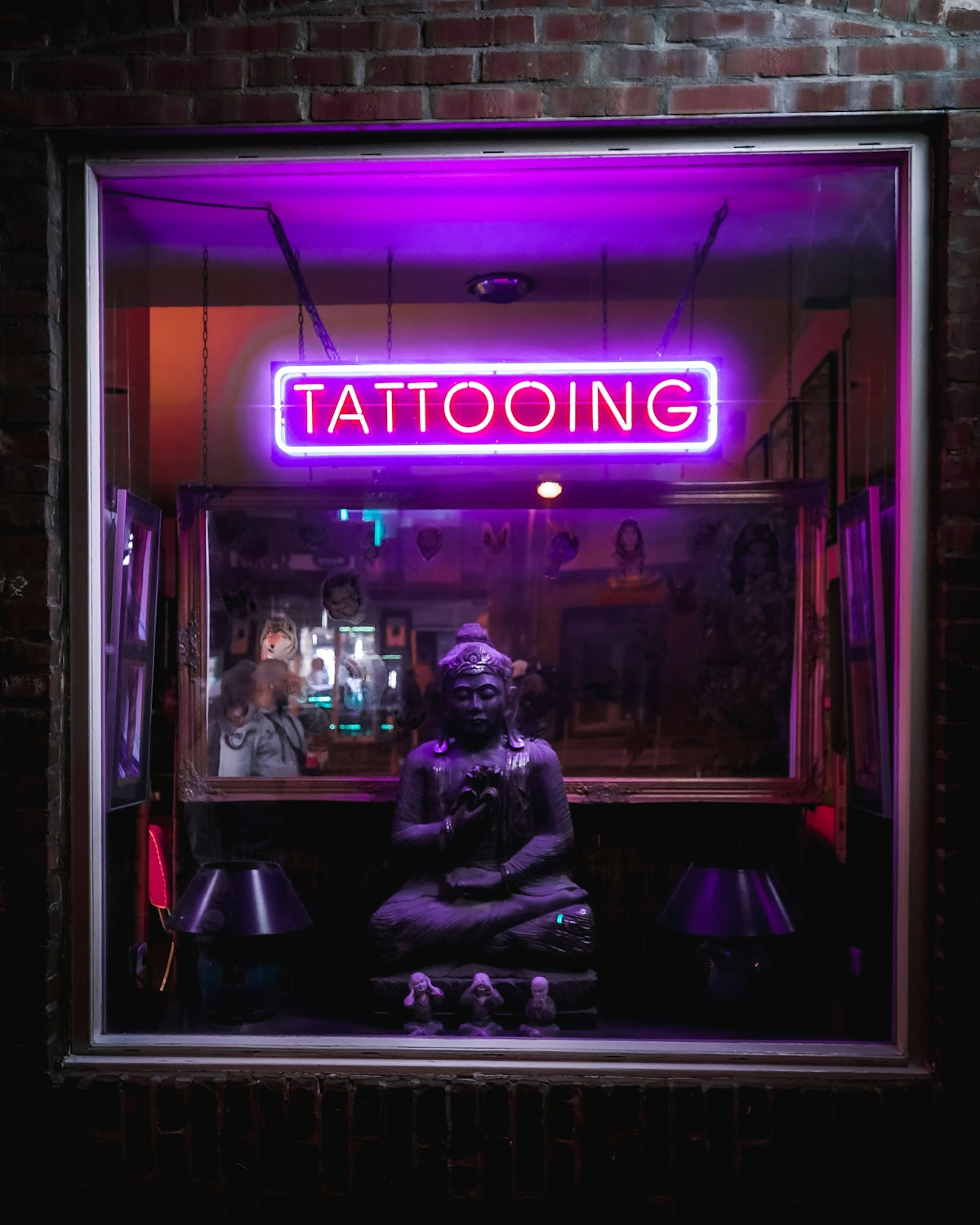 man in black jacket sitting on chair in front of purple and brown UNKs store