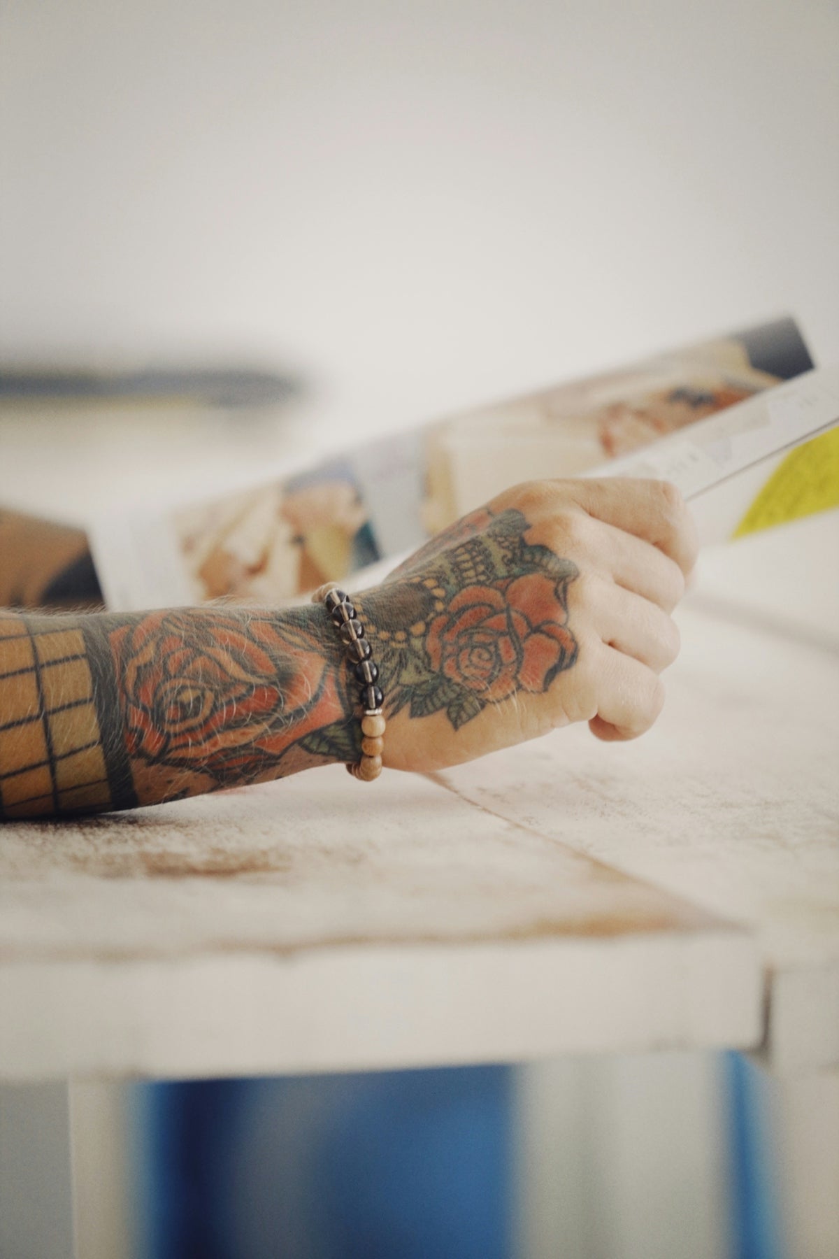 a tattooed arm reading a magazine on a table