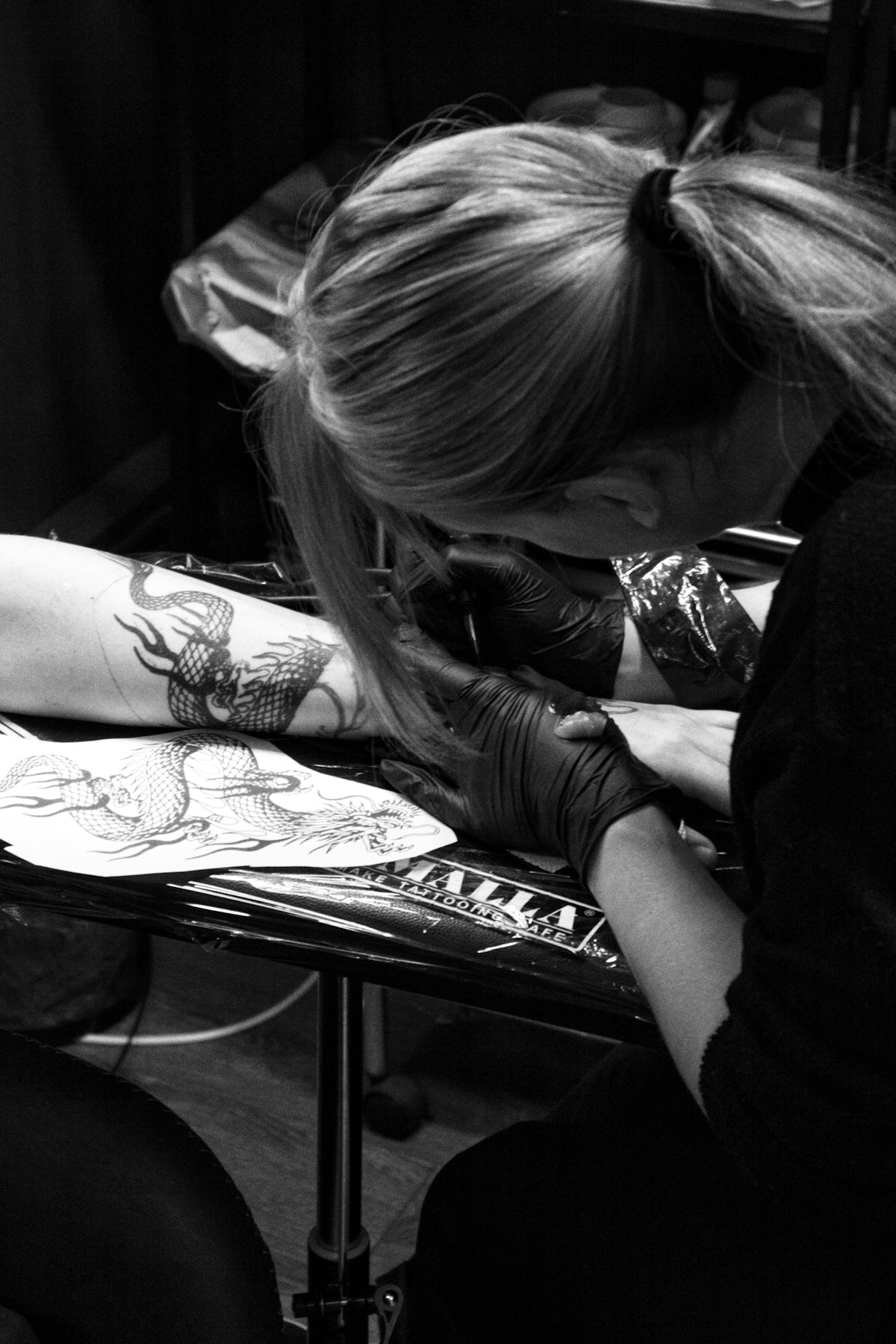 a woman sitting at a table with a tattoo on her arm