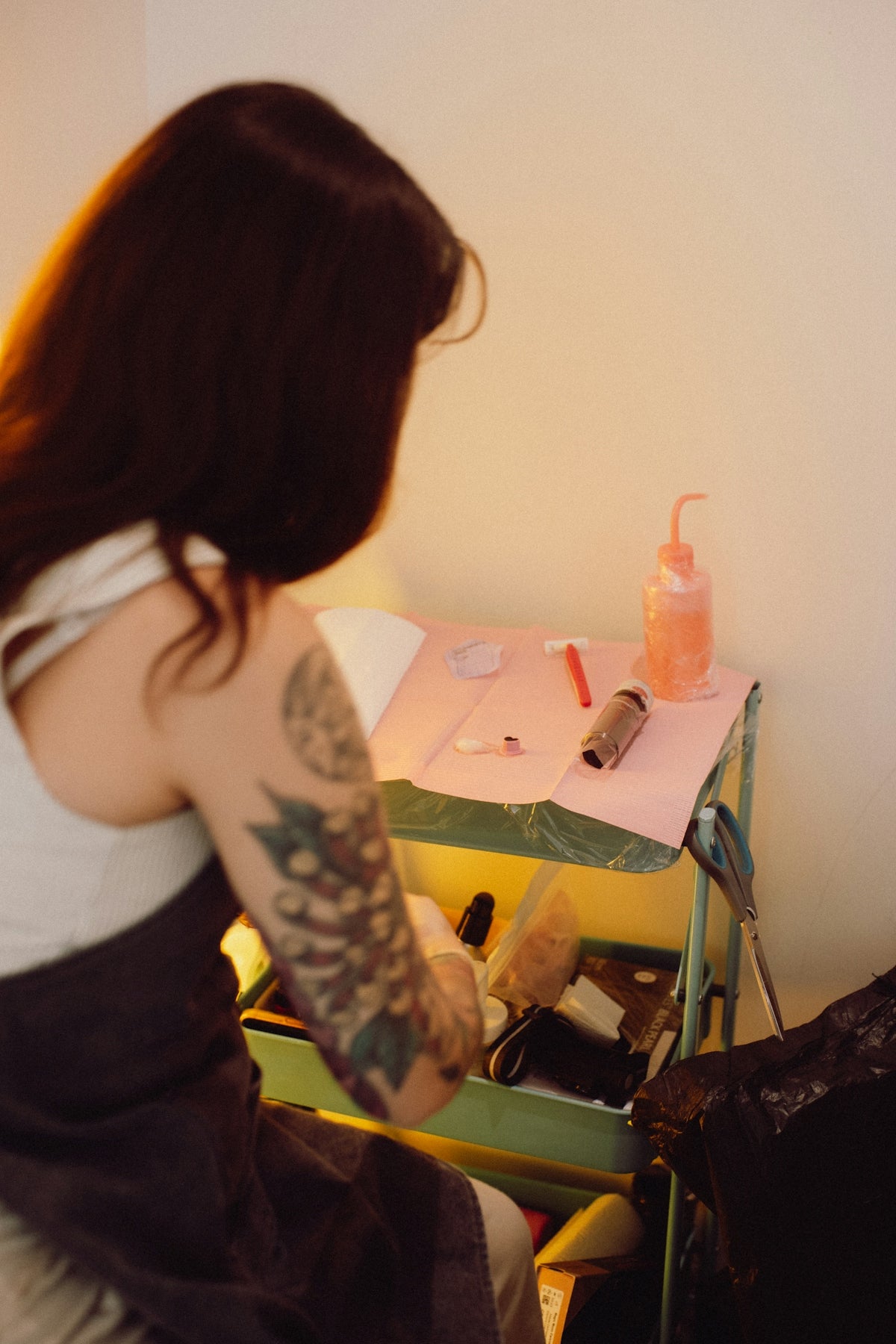 A woman with a tattoo works at a table.