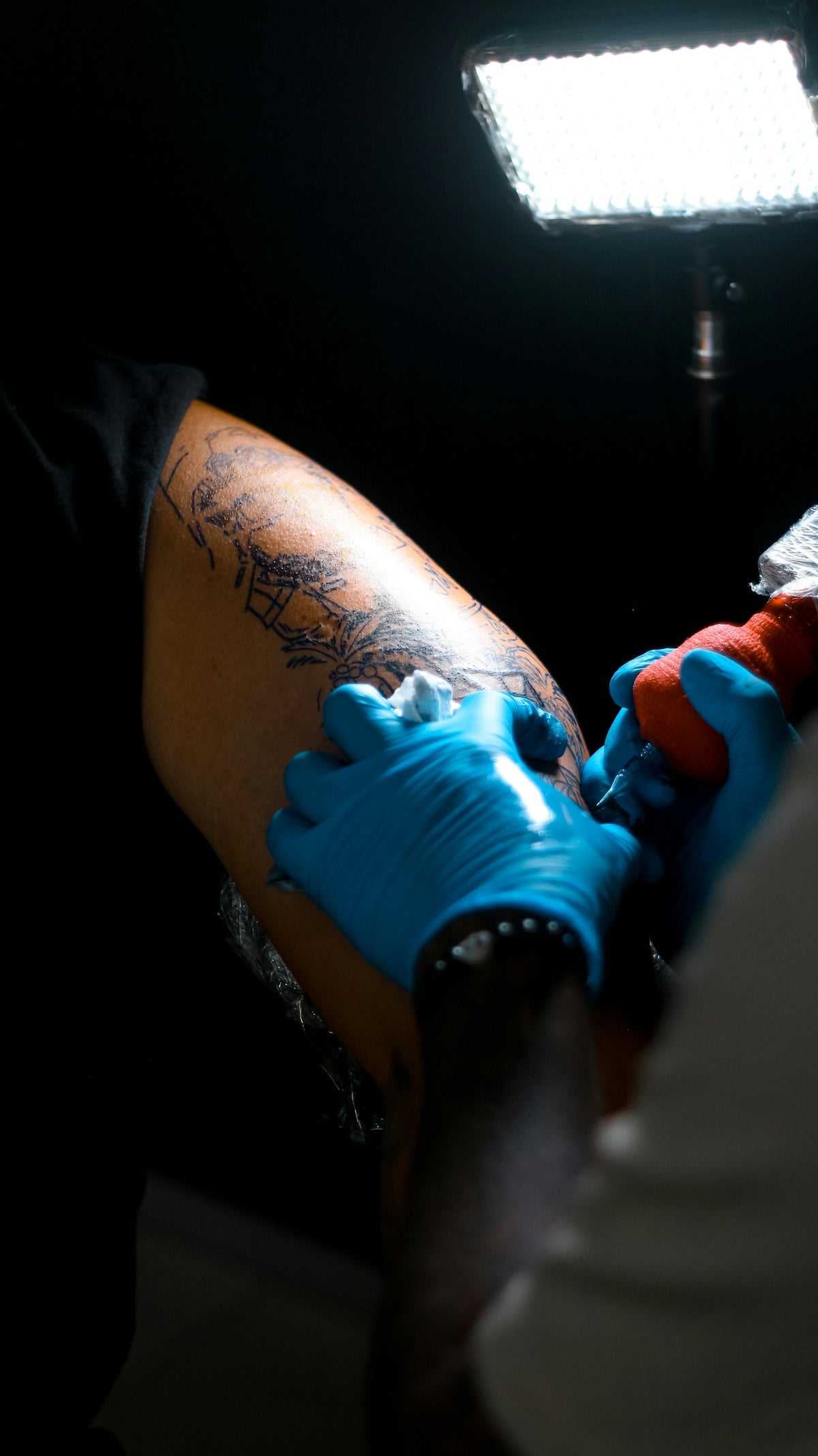 Tattoo artist applying ink to client's arm